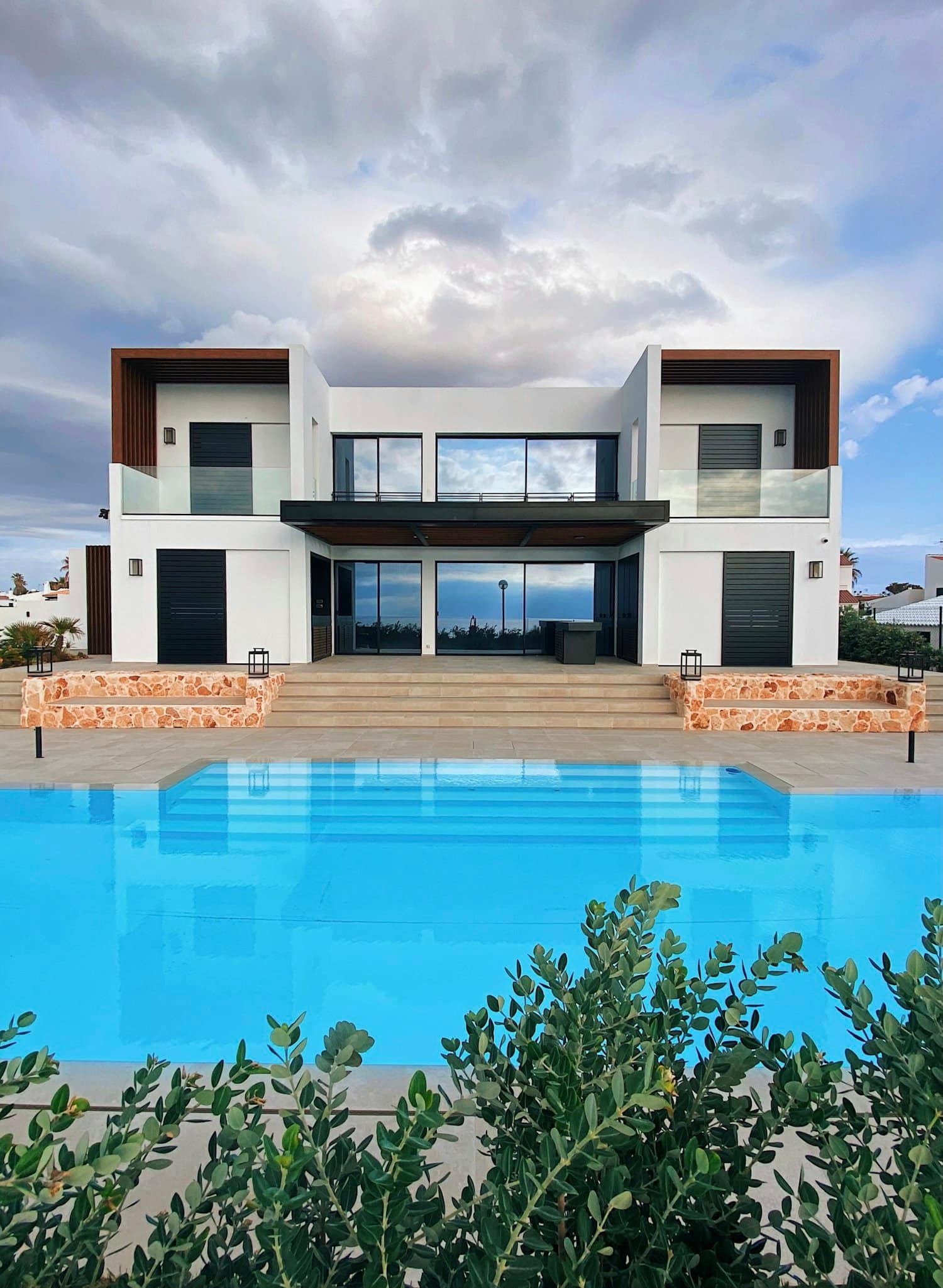 Bodrum kıyısında, mavi havuzlu beyaz taş villa ve zeytin çalıları.
